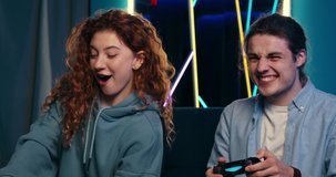 Close-up of two excited people playing video games on console at home. Happy woman gamer winning competition. Lively couple spending time together.
