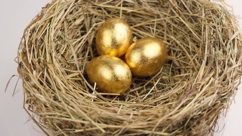 Golden eggs in a straw nest spinning to the right. Easter and financial success concept 