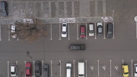 Cars move in the parking lot with marked parking spaces - top view drone shot. Traffic in the parking lot with handicapped spaces near the supermarket.