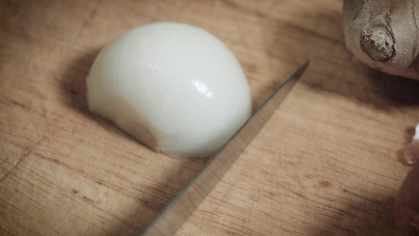 Chef's Hand Rapidly Cutting White Onions On Wooden Chopping Board With Knife. - close up
