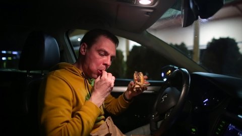 Eating fast food in parking lot. Increasing strength worker driver. Hungry man eating snacks and burger in car. Satisfy your hunger on road. Dine in evening car. 