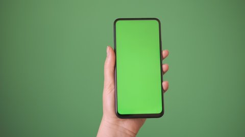 Phone in the hand close up isolated at green background. Phone screen is green chroma key, background chroma key green screen