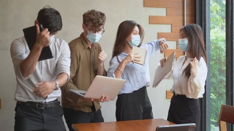 
Cheer up, Dance business people group, teamwork of young asian, caucasian having fun, happy at office after project done, wear face mask protect to pandemic of covid. Celebrating success concept..