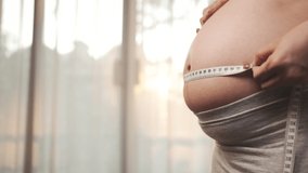 Pregnant woman measuring the size of pregnancy at home, New family baby born concept. - Powered by Shutterstock - Get 15% off with code: PIKWIZARD15