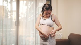 Asian Pregnant woman measuring the size of pregnancy at home, New family baby born concept. - Powered by Shutterstock - Get 15% off with code: PIKWIZARD15