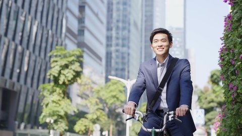 young asian business man riding bike to work in downtown of modern city