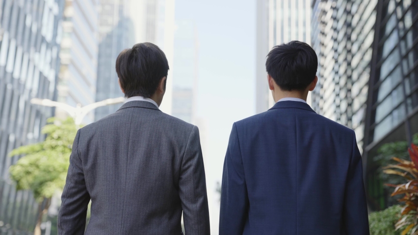 rear view of two asian business men walking talking in the street in downtown  Royalty-Free Stock Footage #1069015075