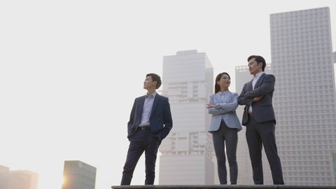 team of three business people standing on top of steps talking chatting with modern city skyline in background