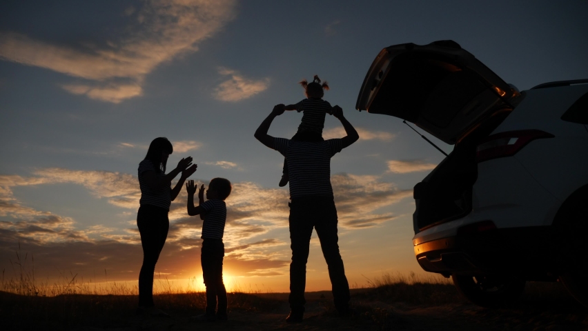 Happy family children kid together standing next to car watching the sunset silhouette in park. journey family travel dream concept. happy family stand with sunlight their backs watching in the park | Shutterstock HD Video #1069016620
