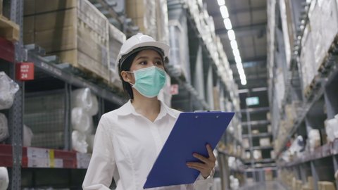 Warehouse worker Asian woman wearing hard hat And a face mask in work. Check Stock the product in factory. Workers work part time. Intention to work professional. Concept Export business