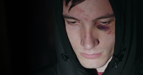 Sad man in hood with bruise and abrasions under the eye