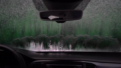 Brush washer in a car wash cleaning the windshield  from inside the car. Weekend routine concept