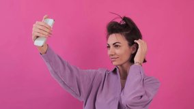 Caucasian woman in casual purple shirt on pink background happy positive smiling take photo video selfie on mobile phone   