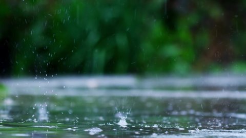 Rainy Day. Rain falling on wet asphalt and creating ripples. Macro shoot of Raindrop fall slow motion footage.