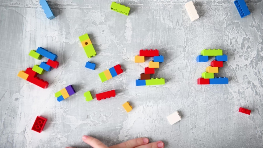 Close-up kids hands building numbers 2022 from colorful constructor blocks on isolated gray background.children’s lego blocks cubes | Shutterstock HD Video #1069027888