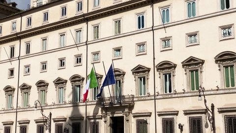 facade of Palazzo Chigi in Rome, seat of the Italian prime minister and government. The Italian and European flags on the balcony of the facade. Outdoors on a sunny day. Politics and democracy 