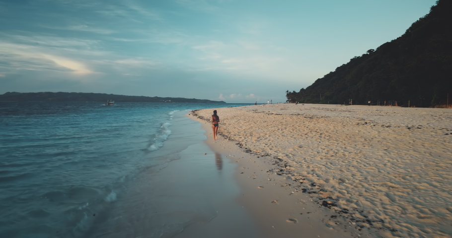 Slow motion of pretty woman running at sea bay aerial. Sunrise over sand tropical beach. Beautiful girl in swimsuit. Beauty model in bikini jogging at water. Summer tropic vacation at Bali, Indonesia | Shutterstock HD Video #1069030660