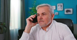 Head shot happy older senior retired man holding mobile phone call with friends, discussing life news at home. Serious middle aged businessman discussing working issues with partners distantly.
