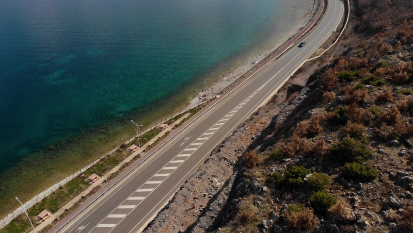Road alongside beautiful lake shore with calm crystal water, travel concept