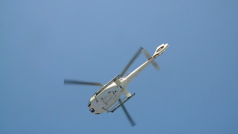 Helicopter take off in slow motion. Taken from under side showing bell of heli and rotor spinning.
