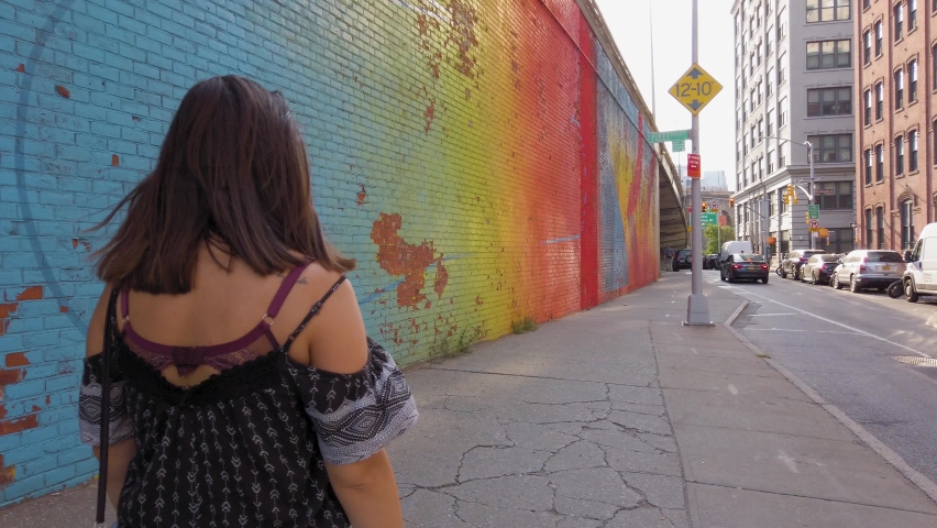 Young girl walking in front of a colourful wall in New York City 