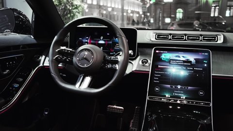 The driver's seat, front dashboard with new touchscreen displays and steering wheel in the interior of the newest Mercedes.-Benz S-Class W223. Closeup cinematic 4k shot. Moscow, Russia - March, 2021.