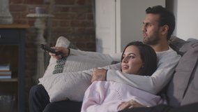 Evening shot of couple lying and relaxing on lounge sofa at home and watching TV together - shot in slow motion - Powered by Shutterstock - Get 15% off with code: PIKWIZARD15