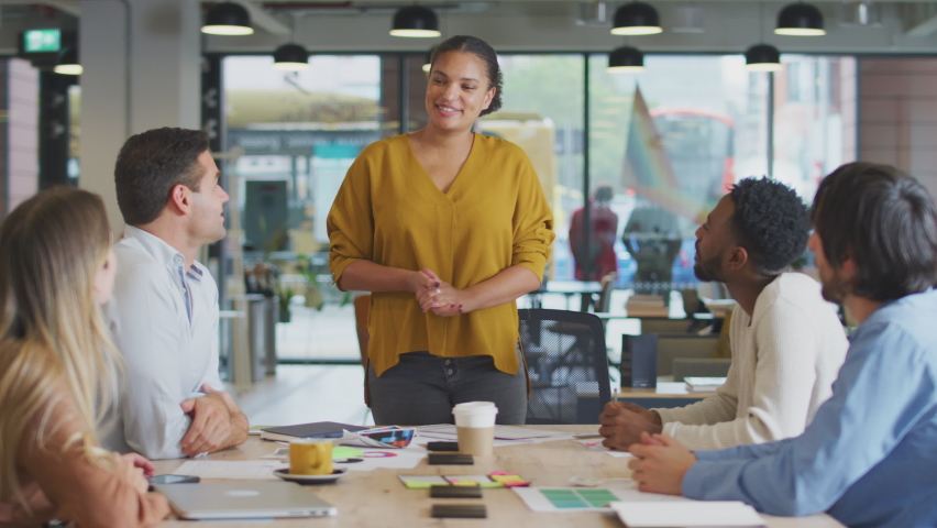 Standing businesswoman leading meeting to colleagues around table in modern office - shot in slow motion Royalty-Free Stock Footage #1069050772