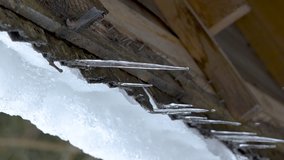 Ice are melting on the side of the roof of the small cabin during the winter in Estonia vertical video