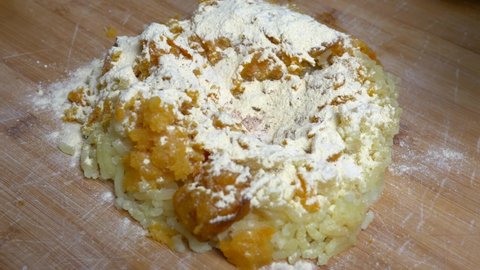 Woman hand puts flour on dough for preparing homemade pumpkin and potato gnocchi. Homemade pasta preparation. Slow motion 4K