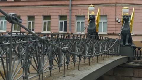 bank bridge in St. Petersburg is guarded by Griffins with golden wings attraction of townspeople and tourists blurry movement of people, time lapse