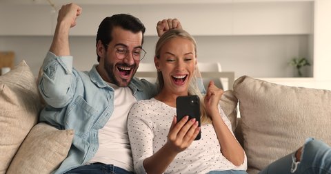 Young couple use smartphone read great offer sms opportunity scream with joy feel excited celebrate success. Moment of online lottery victory, unbelievable news, e-commerce sale, happy clients concept