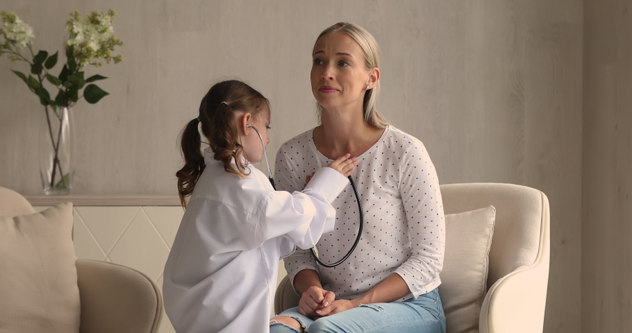 Adorable little wear white coat uniform play doctor take care of mother holds stethoscope listens to mom heartbeat. Funny playtime with kid at home, cardiologist profession in future, vocation concept Royalty-Free Stock Footage #1069059436