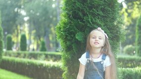 Pretty little child girl standing outdoors in green summer park pointing up with her finger.