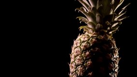  Rotate Video footage of a pineapple on black background.