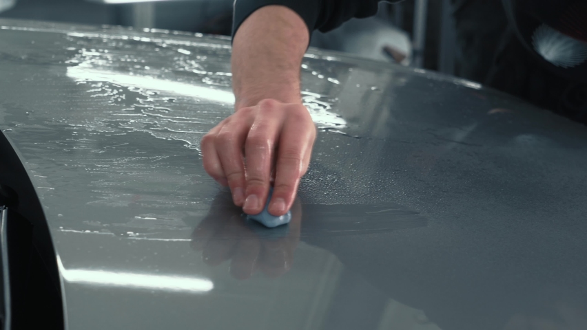 Worker clean car body with blue clay for cleaning before installing protective layer or PPF coating to auto. Car detailing concept Royalty-Free Stock Footage #1069069477