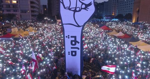 Beirut, Lebanon 2019 : drone track back shot from the revolution fist while protesters are waving with their phone flashlight revolting against government corruption during the Lebanese revolution