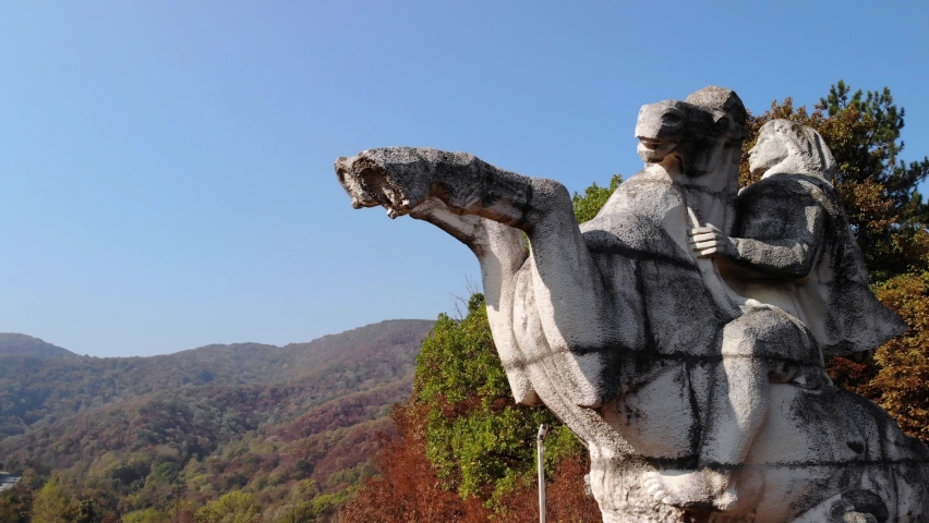 Horse Rider Statue Against Blue Sky With Autumn Forest Mountain At Background In Targovishte, Bulgaria. - Aerial Shot, close up