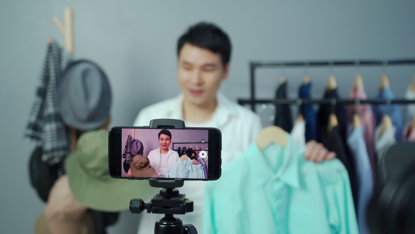 Young man selling clothes and accessories online by smartphone live streaming, business online e-commerce at home | Shutterstock HD Video #1069077646