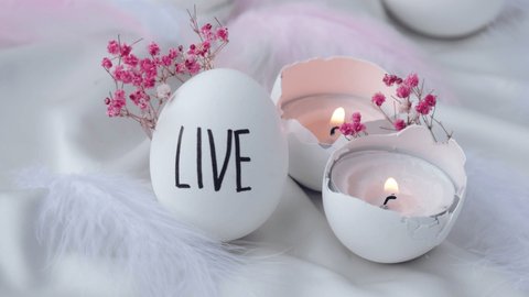 Footage of igniting a candle in Easter eggs Composition. Words drawn with pen. Live. Cozy home interior decor, burning candles hygge, decoration and easter concept - candles burning