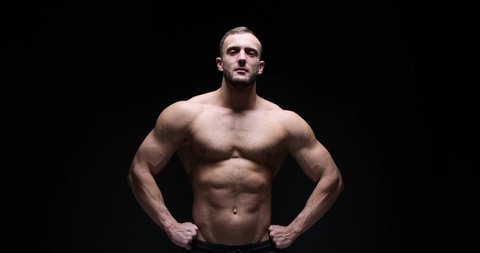Muscular man posing with arms akimbo