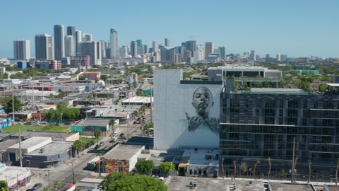 Miami, June 2019. Scenic vibrant colorful urban murals covering modern building walls. Aerial view of street graffiti with Miami beach downtown on motion background. Street art footage in USA city