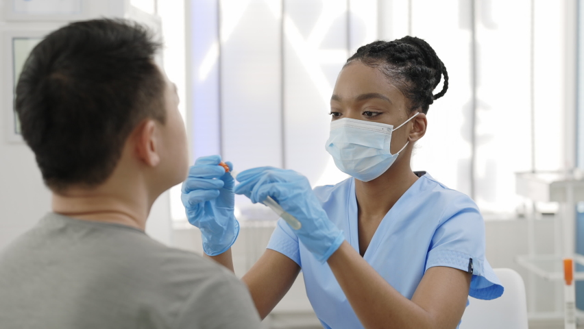 Crop view of medical female worker in protective mask and gloves taking PCR test sample from man in hospital room. Concept of Covid reaesearch and diagnostic. | Shutterstock HD Video #1069087477