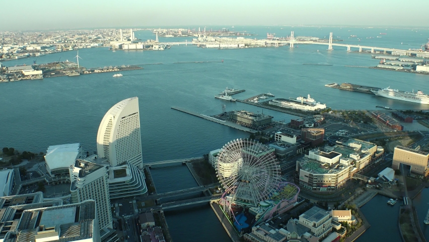 YOKOHAMA, JAPAN : Aerial sunset cityscape of “Minatomirai area“. Seaside urban area in central Yokohama city. View of buildings around the harbor or port or bay. Time lapse zoom out shot dusk to night