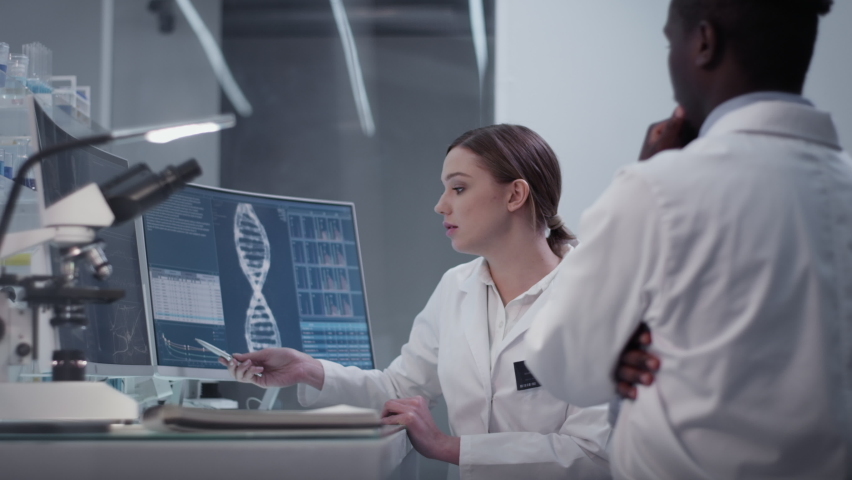 Diverse scientists discussing while studying human skeleton. Using computers and microscopes. Modern laboratory interior | Shutterstock HD Video #1069089352