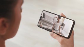 Online yoga practice. Close up shot of young woman watching video lesson of pilates and stretching on smartphone