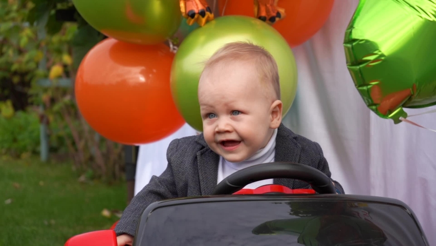 Kid in a jacket with birthday balloons