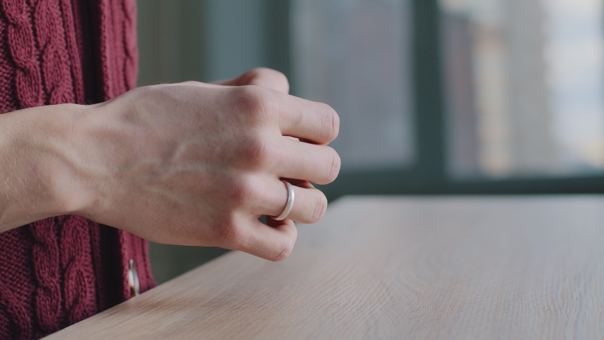 Close-up of male hands, cropped shot frustrated divorced deceived caucasian man husband takes off wedding ring puts on wooden table decides to separate, breakup marriage concept, end of relationship. Royalty-Free Stock Footage #1069097770