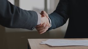 Close up male hands multiethnic caucasian and afro business people men shaking successful corporate partnership deal, making handshake in office, congratulating with signing of contract documents. - Powered by Shutterstock - Get 15% off with code: PIKWIZARD15