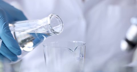 Scientist chemist pouring water from flask into glass 4k movie